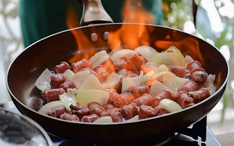 Sausages and onions cooking in a flaming pan during a Brazilian cooking class in Copacabana, Rio de Janeiro.