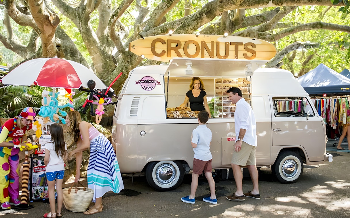 Cronut van at Eumundi Markets with people buying pastries and browsing stalls.