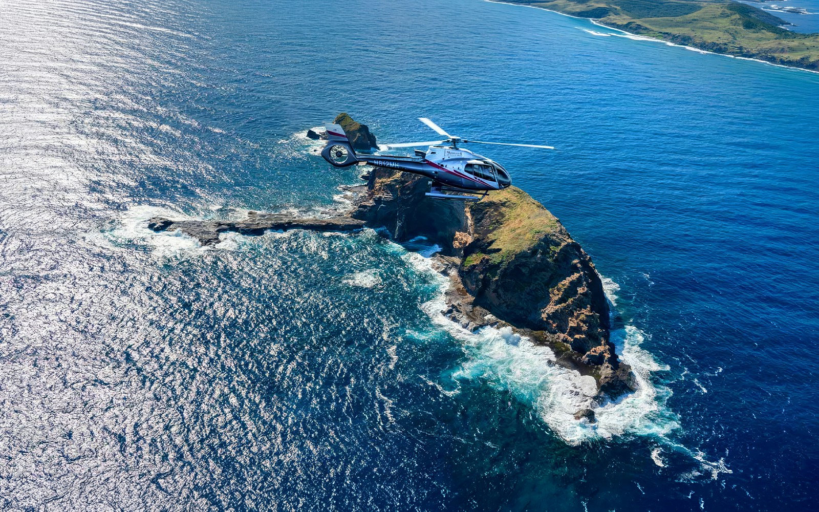 Helicopter flying over ocean and cliffs in Maui, Hawaii during tour.