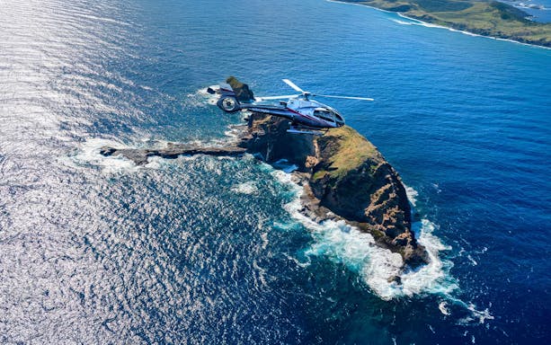 Helicopter flying over ocean and cliffs in Maui, Hawaii during tour.