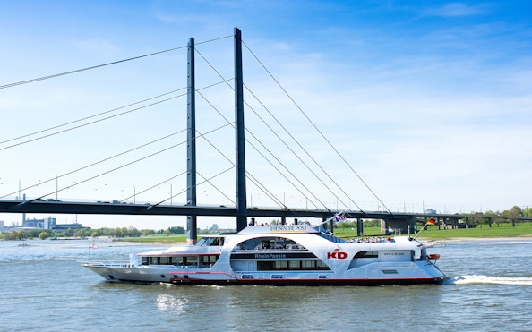 Cruise ship on the Rhine River passing under a bridge in Düsseldorf.