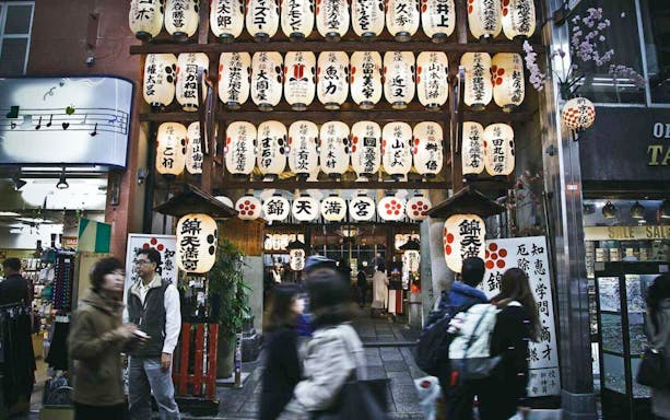 Kyoto street with traditional lanterns and people walking, part of guided tour.