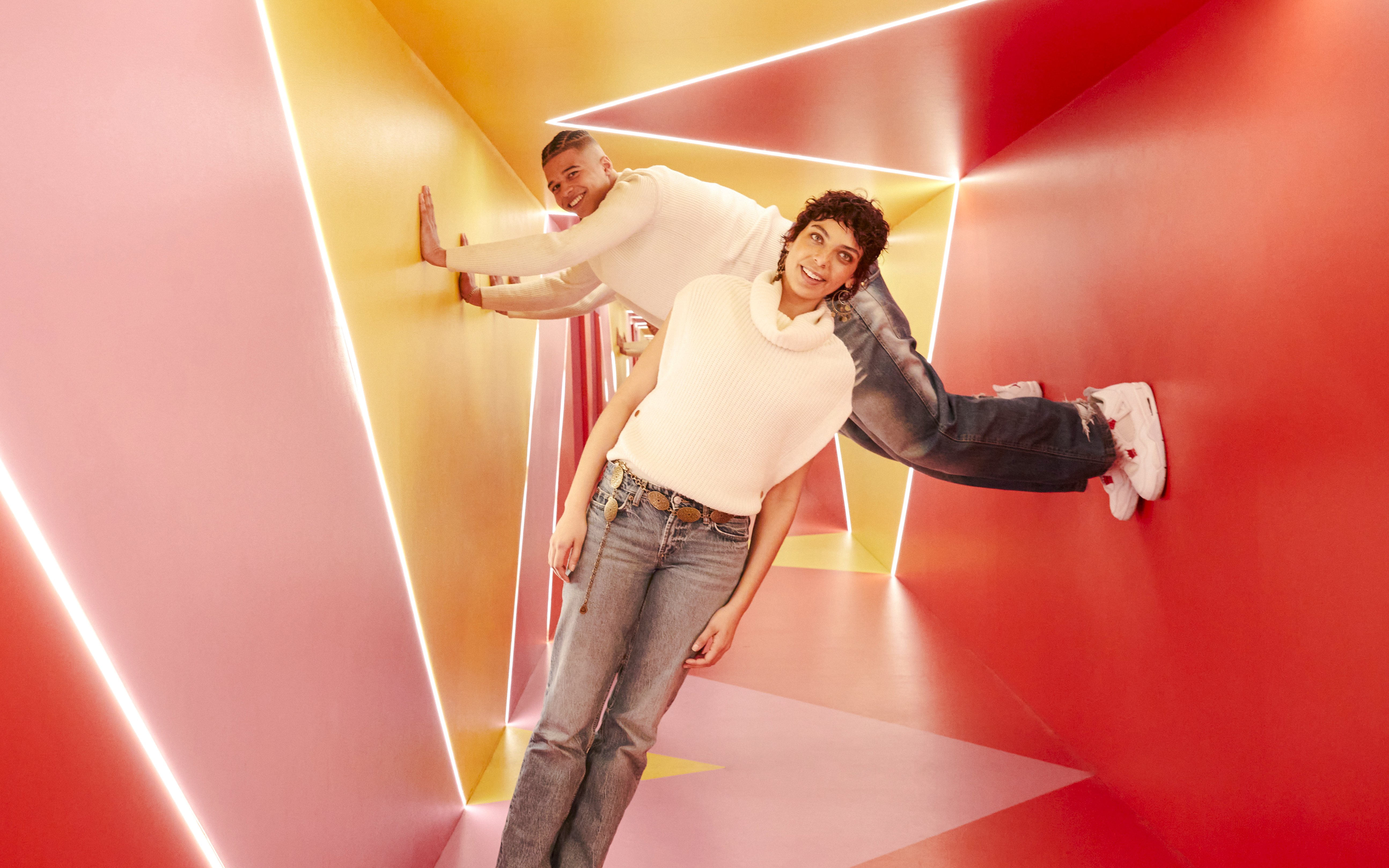 Visitors exploring colorful geometric hallway at Twist Museum, London.