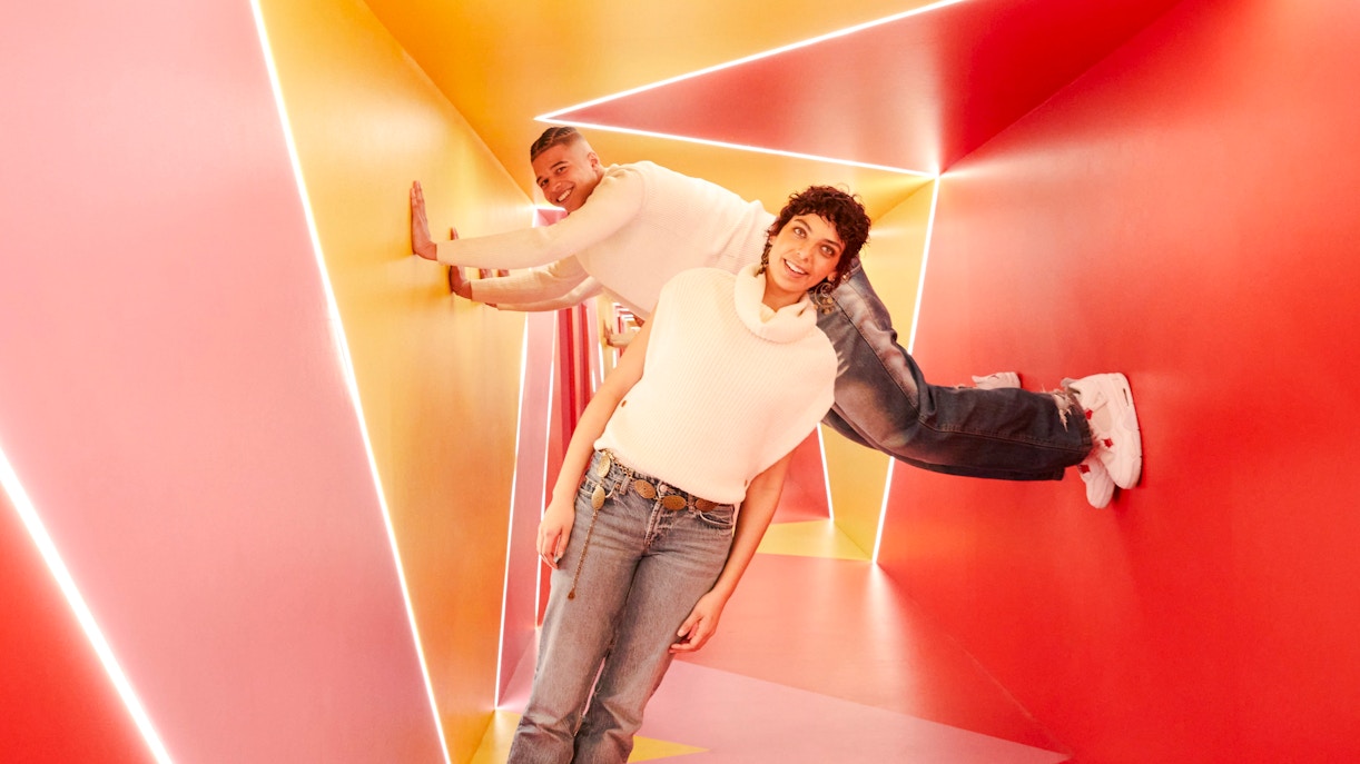 Visitors exploring colorful geometric hallway at Twist Museum, London.