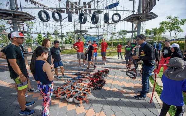 Group preparing for ropes course at Discovery Park, Gamuda Cove, with harnesses and helmets.