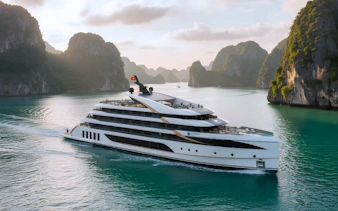 Luxury cruise ship sailing through Ha Long Bay with limestone karsts in the background.