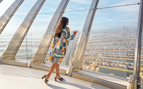 Person enjoying panoramic view of Palm Jumeirah from The View at The Palm observatory.
