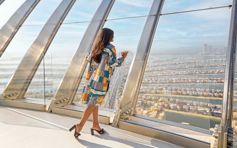 Person enjoying panoramic view of Palm Jumeirah from The View at The Palm observatory.
