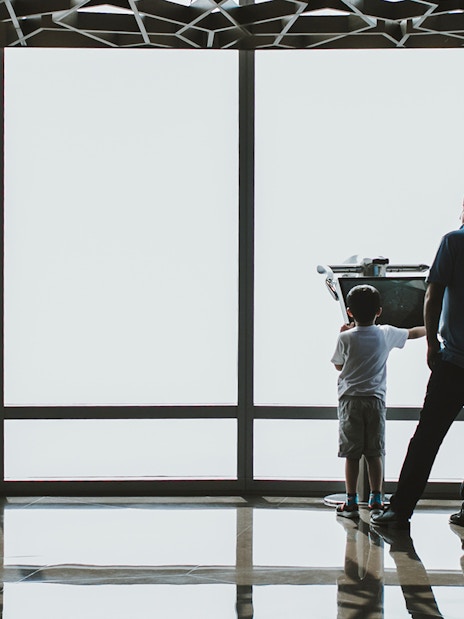 Child and adult using a telescope at Burj Khalifa observation deck, Dubai.