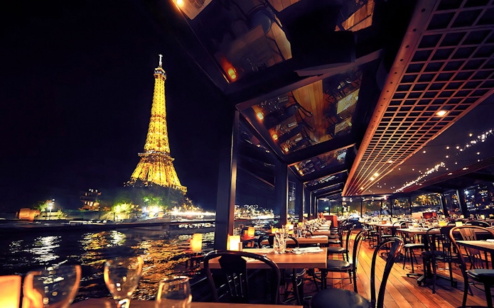 Seine River cruise dining with Eiffel Tower view at night, Paris.