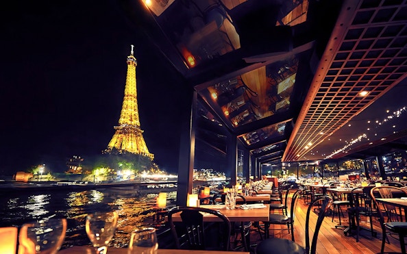 Seine River cruise dining with Eiffel Tower view at night, Paris.