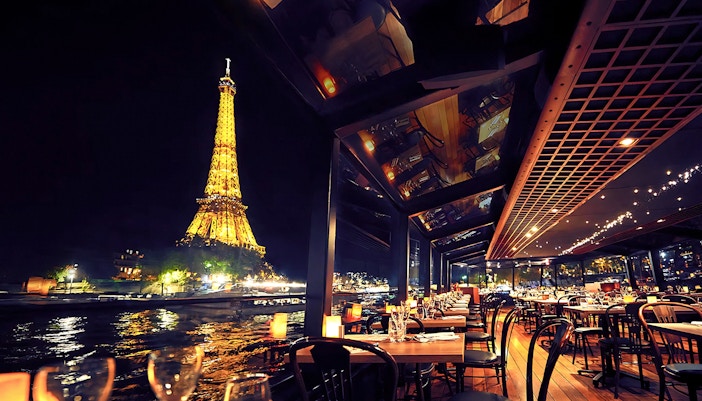 Inside the Maxim's Seine River Cruise at night with a view of Eiffel Tower.