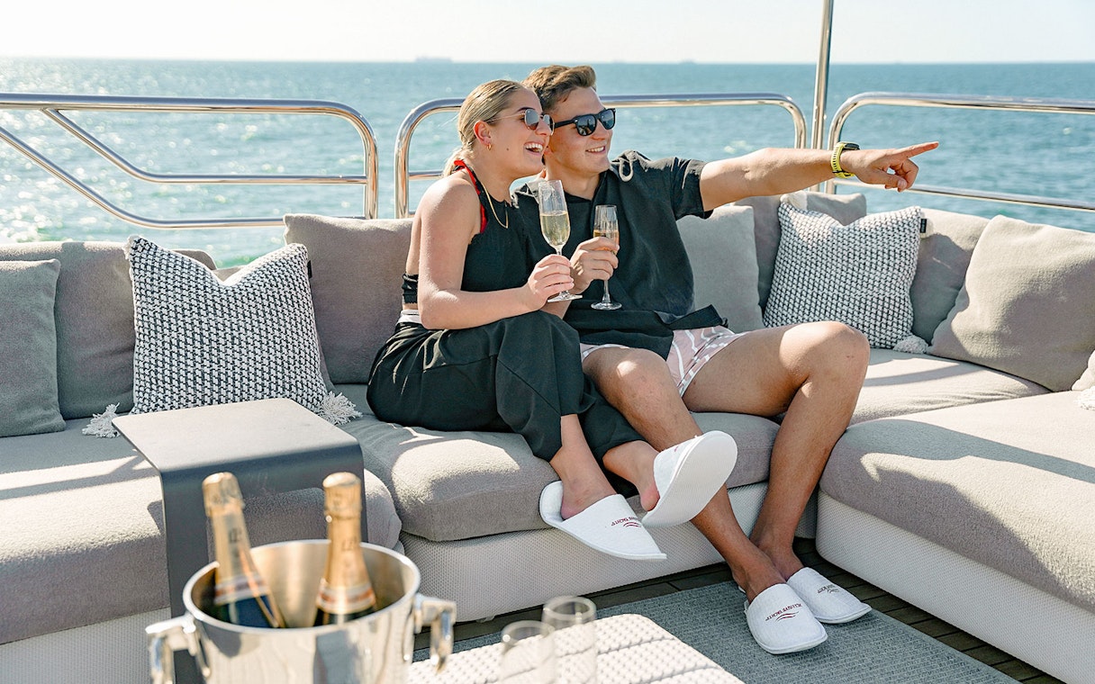 Couple enjoying champagne on a Sunseeker superyacht with ocean view.