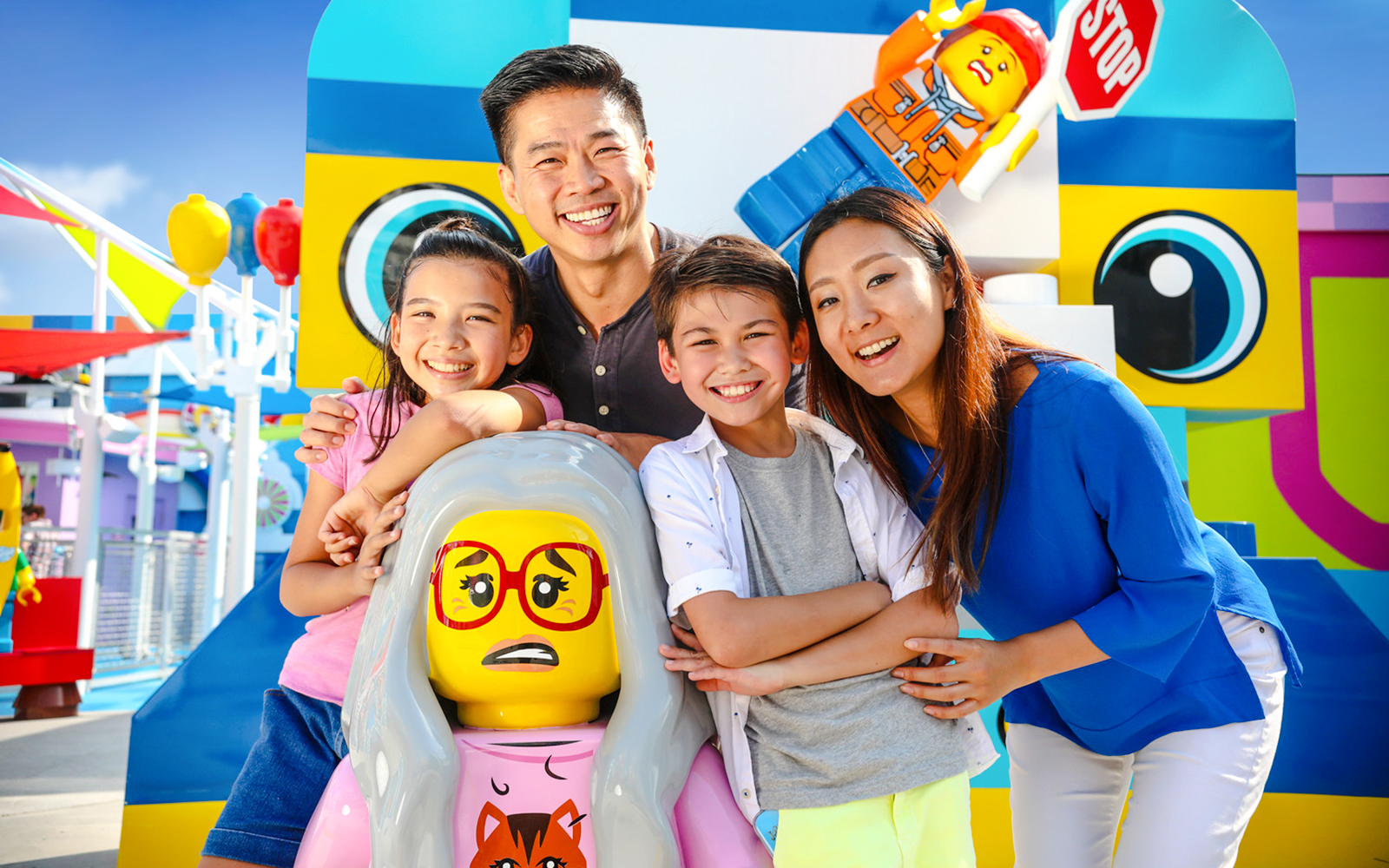 Family enjoying a day at LEGOLAND® California with colorful LEGO figures in the background.