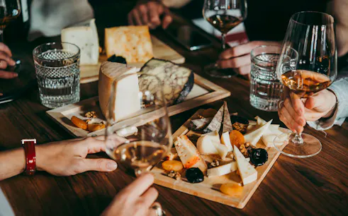Wine and cheese tasting at a hidden wine bar in Paris with assorted cheeses and glasses of wine.