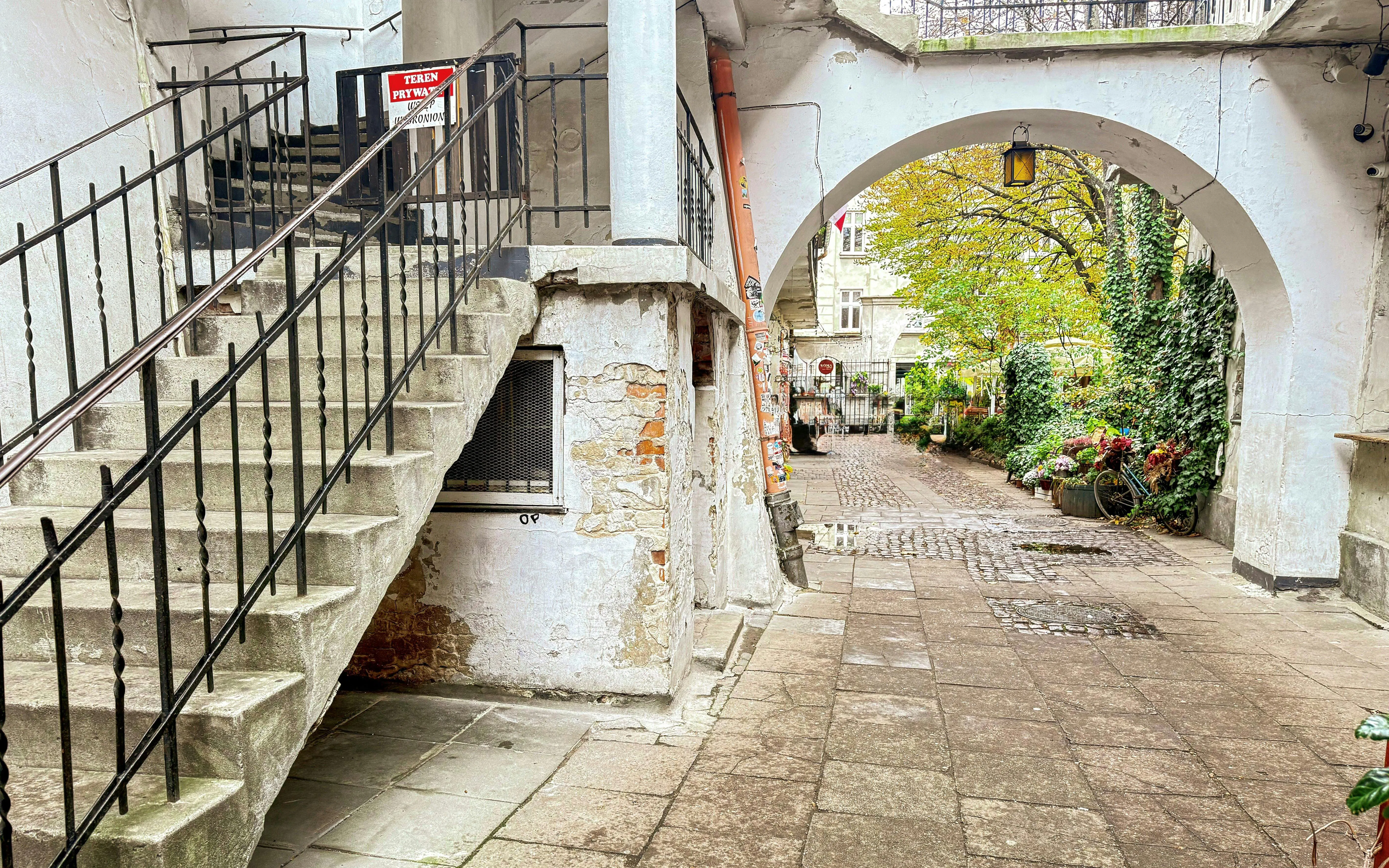 Courtyard in Krakow's Kazimierz district with historic staircase and archway.