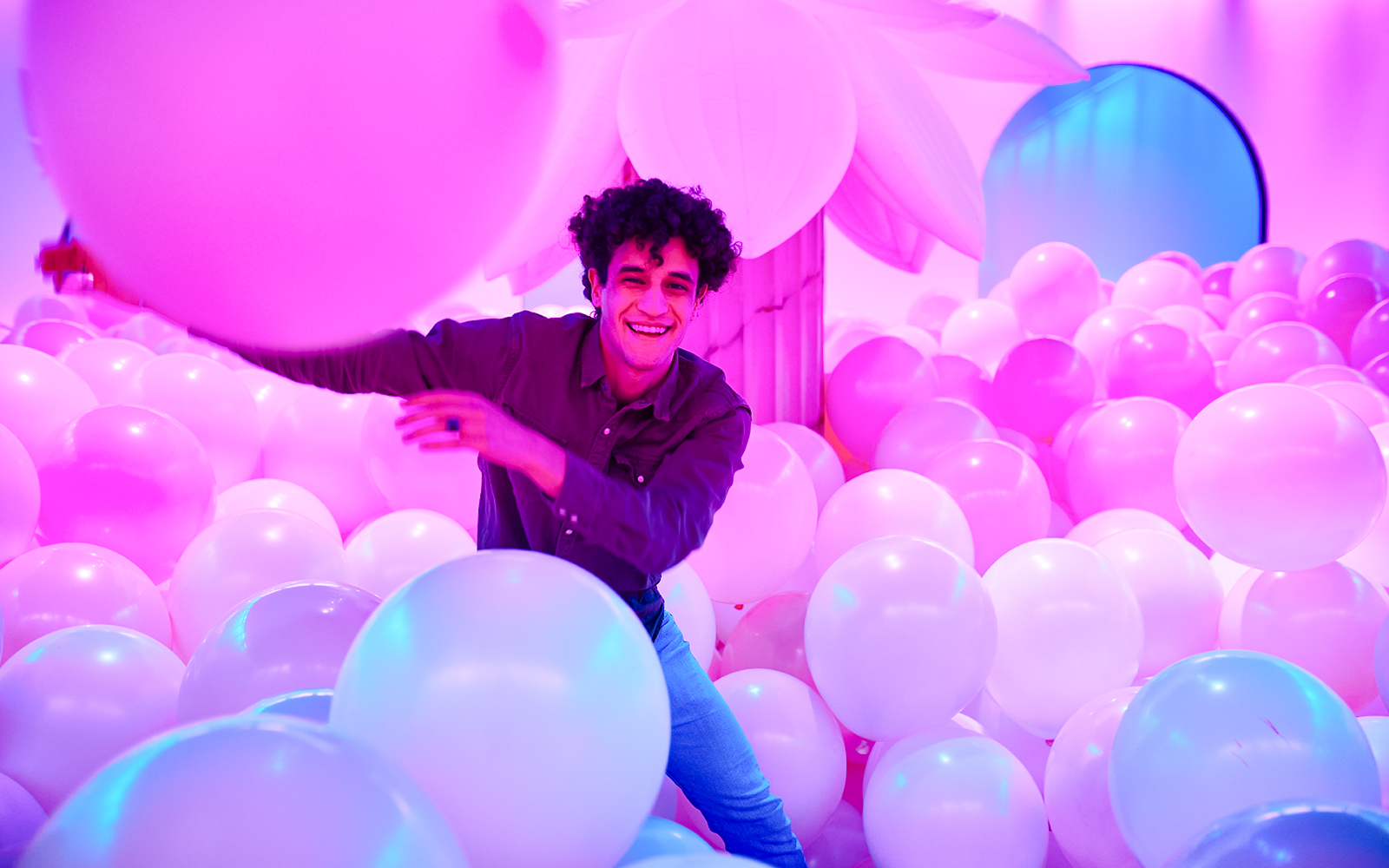 Person enjoying a room filled with pink and white balloons at Bubble Planet, Washington DC.