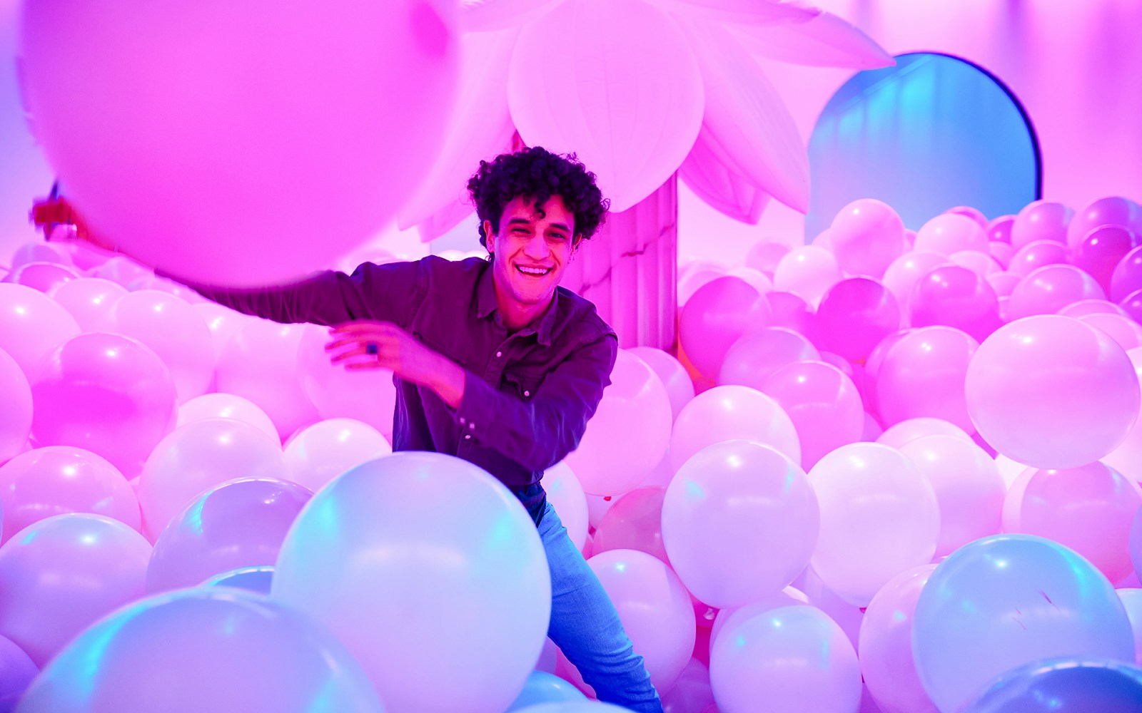 Person enjoying a room filled with pink and white balloons at Bubble Planet, Washington DC.