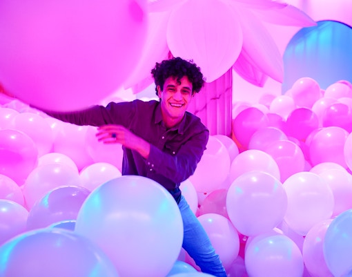Person enjoying a room filled with pink and white balloons at Bubble Planet, Washington DC.