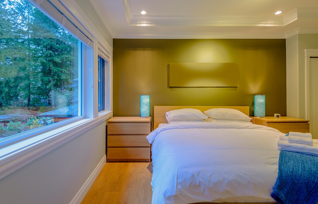 Luxury hotel room with a large bed, modern decor, and forest view through a wide window.