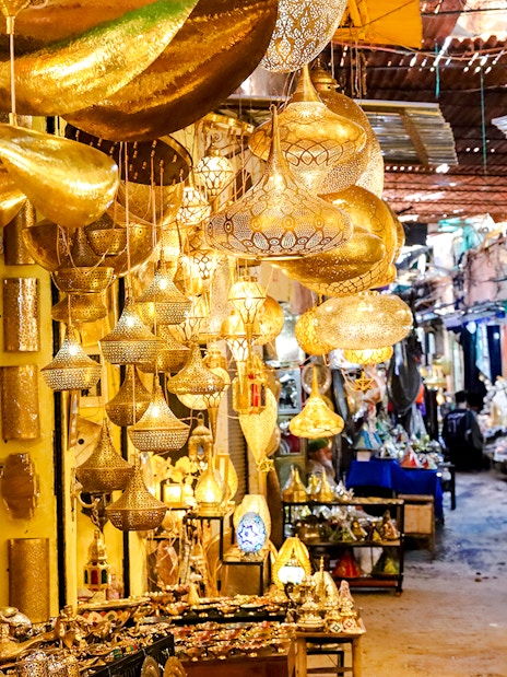 Marrakech souk with ornate golden lamps and vibrant market stalls.
