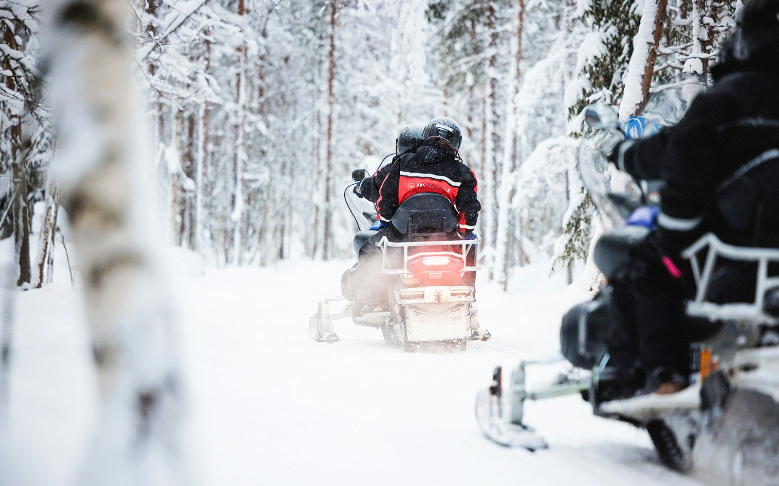 Snowmobile tour through snowy forest in Lapland.