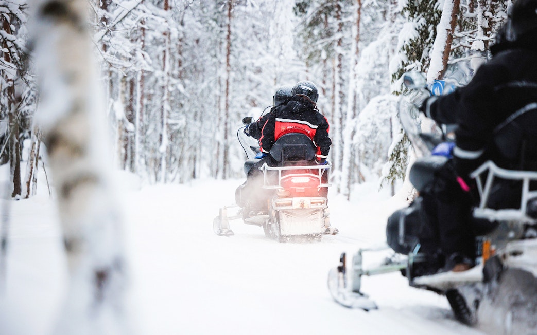 Snowmobile tour through snowy forest in Lapland.
