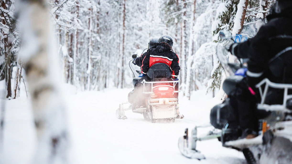 Snowmobile tour through snowy forest in Lapland.