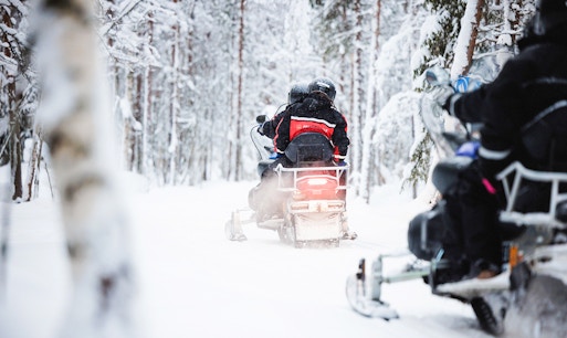 Snowmobile tour through snowy forest in Lapland.