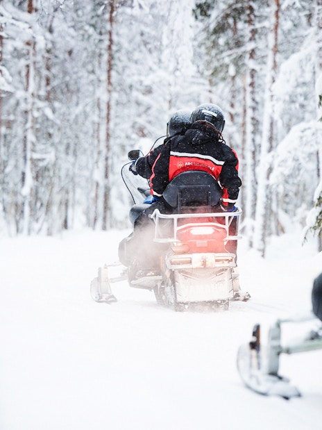 Snowmobile tour through snowy forest in Lapland.
