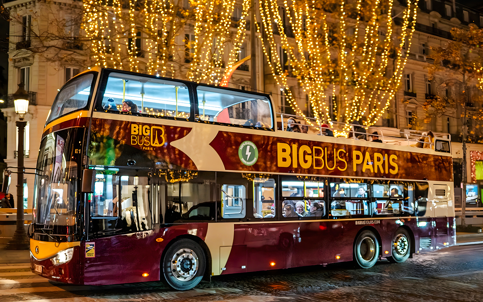 Paris hop-on hop-off bus with Christmas lights at night.