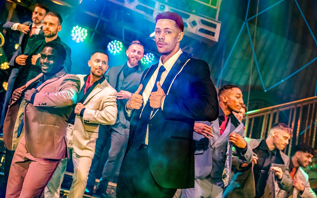 Performers in suits on stage at Magic Mike Live show.