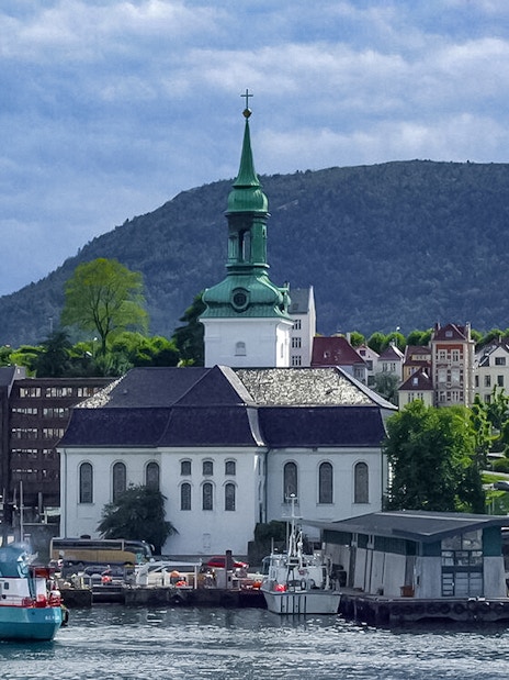 Bergen waterfront with historic church and buildings during sightseeing cruise.