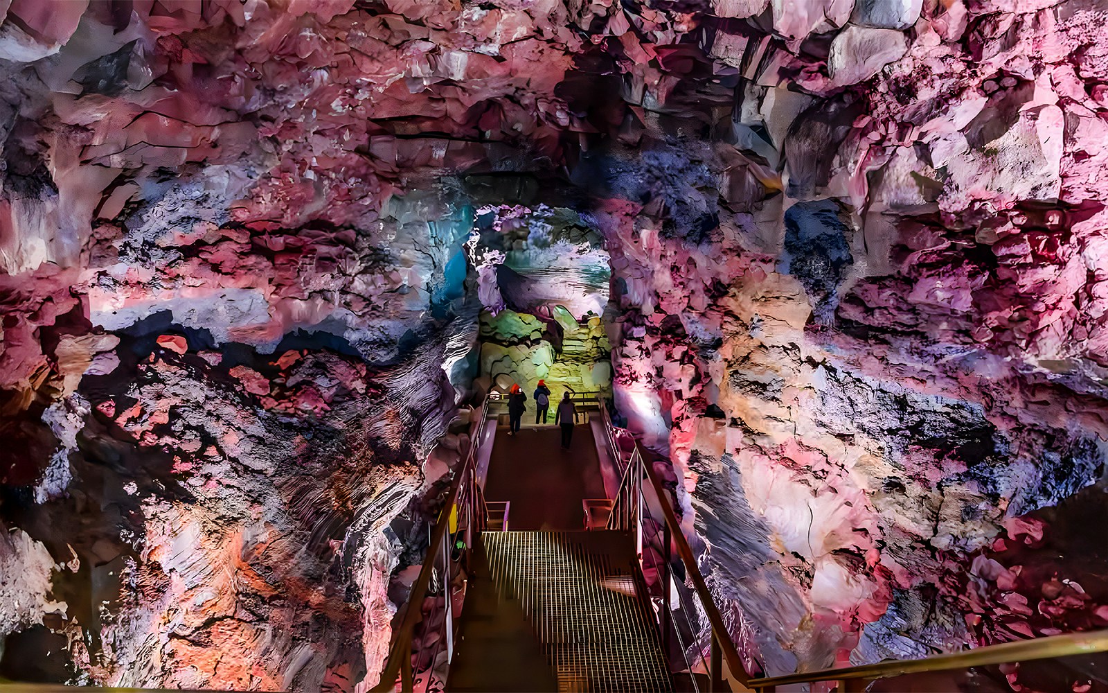 Guests walking on a metal bridge inside Raufarhólshellir Lava Cave, Iceland.
