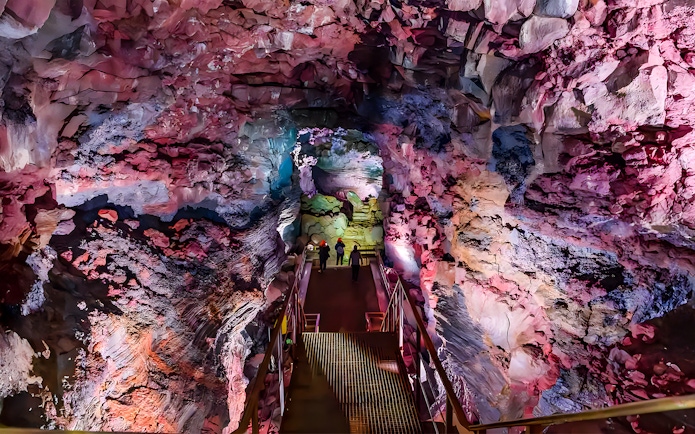 Guests walking on a metal bridge inside Raufarhólshellir Lava Cave, Iceland.