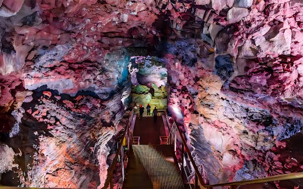 Guests walking on a metal bridge inside Raufarhólshellir Lava Cave, Iceland.