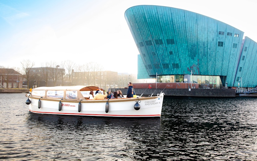 Open boat cruise near NEMO Museum in Amsterdam with passengers enjoying the view.