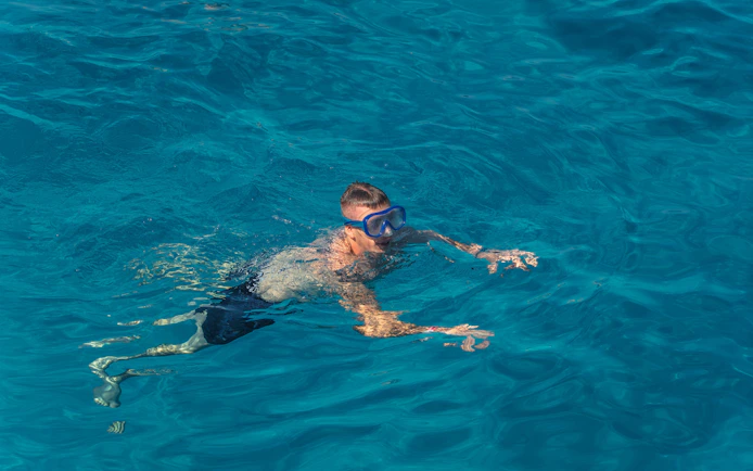 Snorkeler in clear waters at Cala Bassa Beach, Ibiza, Spain.