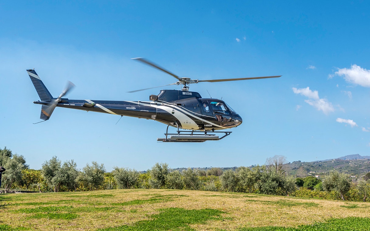 Helicopter flying over green landscape near Etna Volcano, Sicily.
