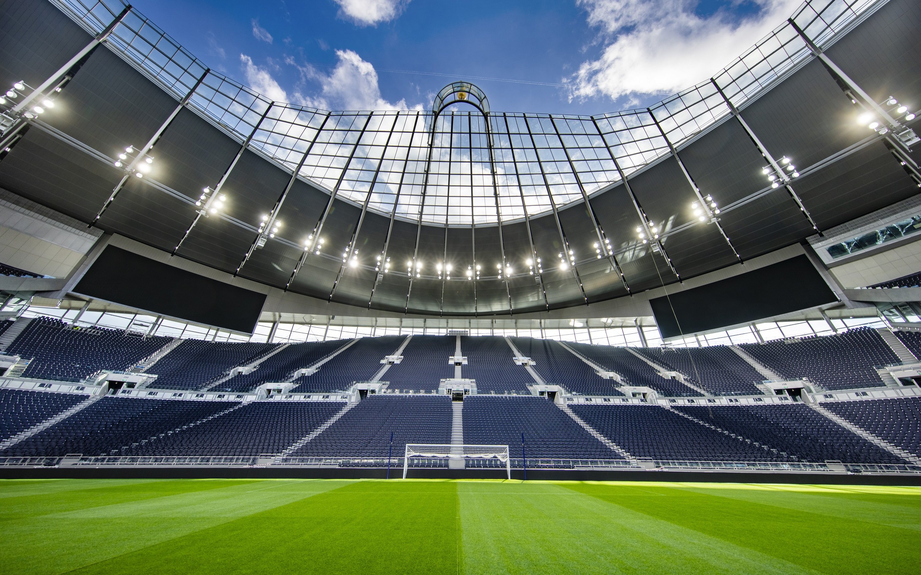 Modern stadium with empty seats and a clear view of the field under a bright sky.