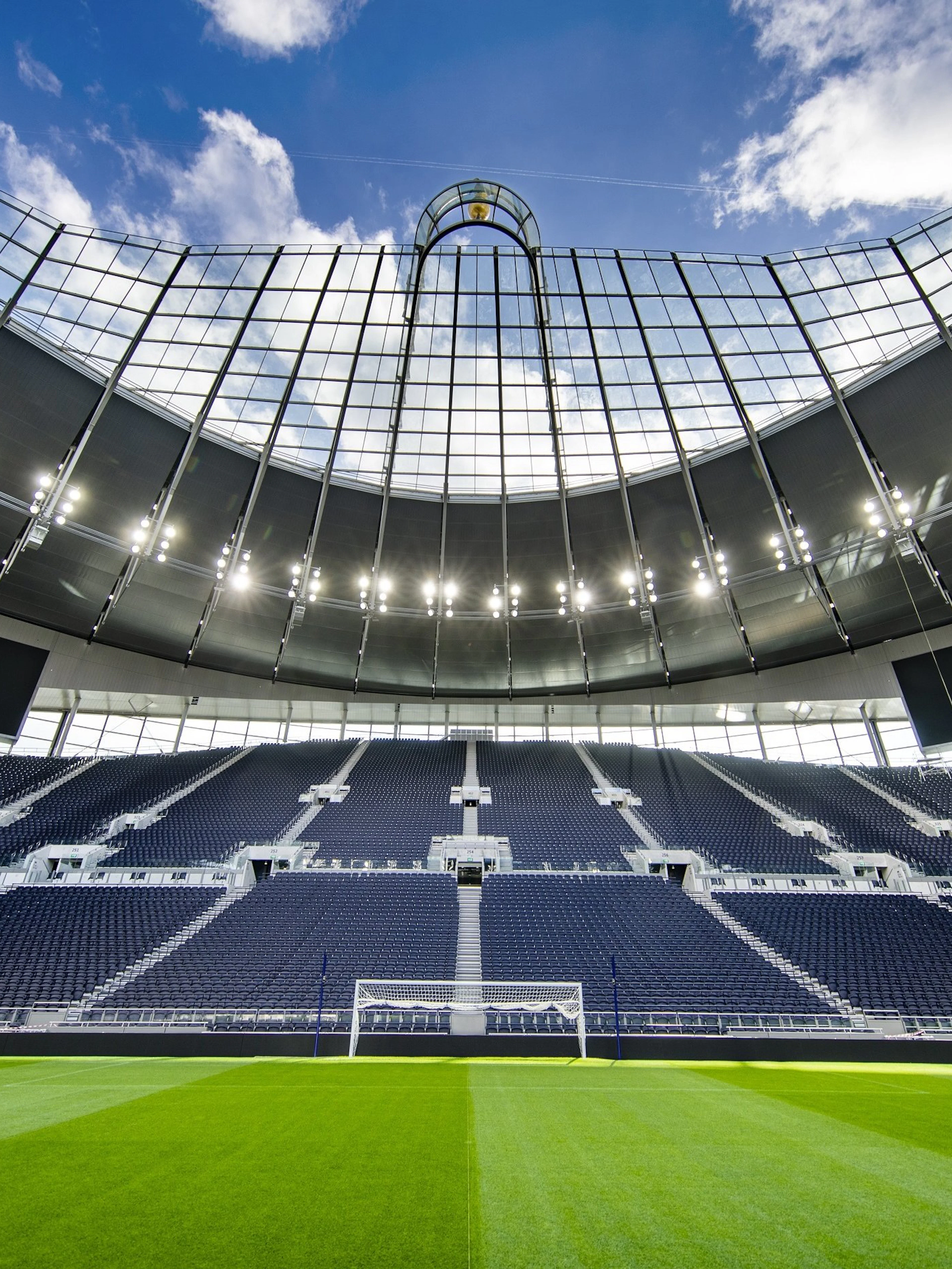 Modern stadium with empty seats and a clear view of the field under a bright sky.