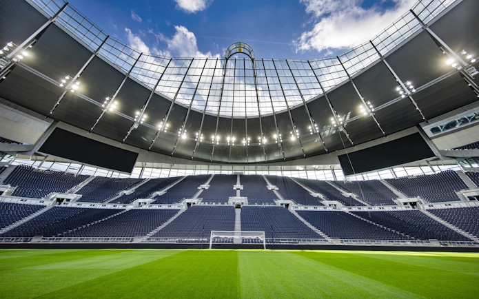Modern stadium with empty seats and a clear view of the field under a bright sky.