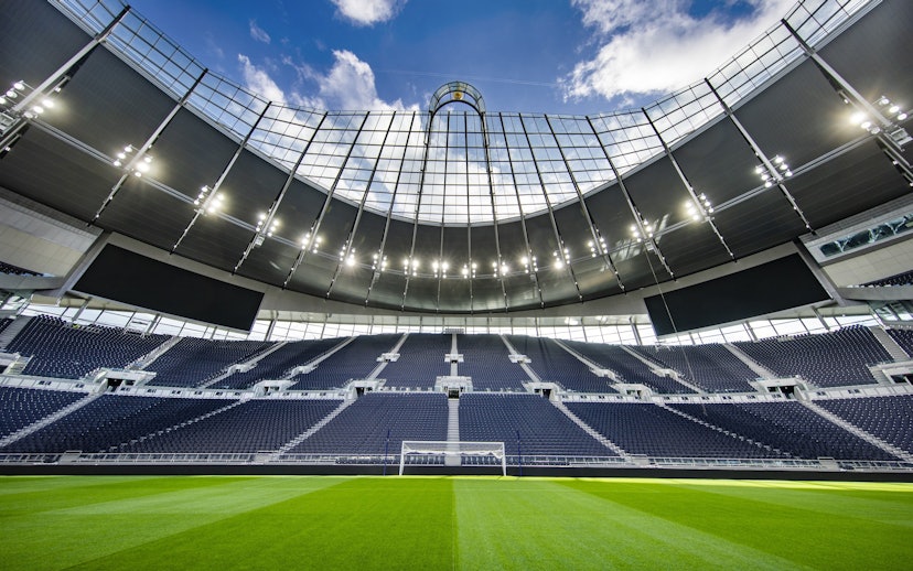 Modern stadium with empty seats and a clear view of the field under a bright sky.