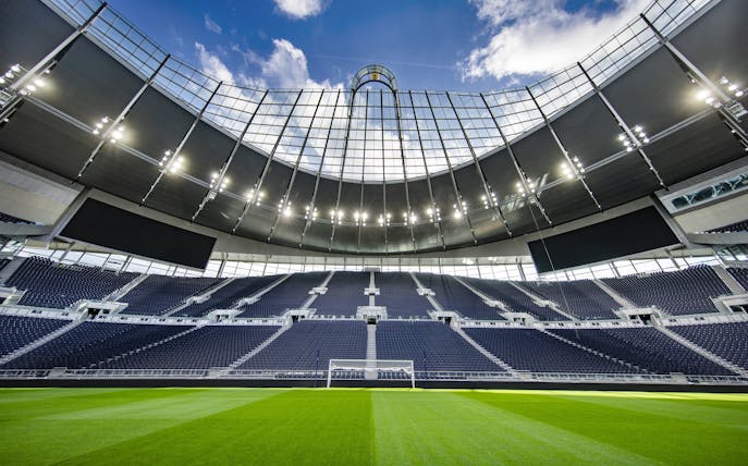 Modern stadium with empty seats and a clear view of the field under a bright sky.