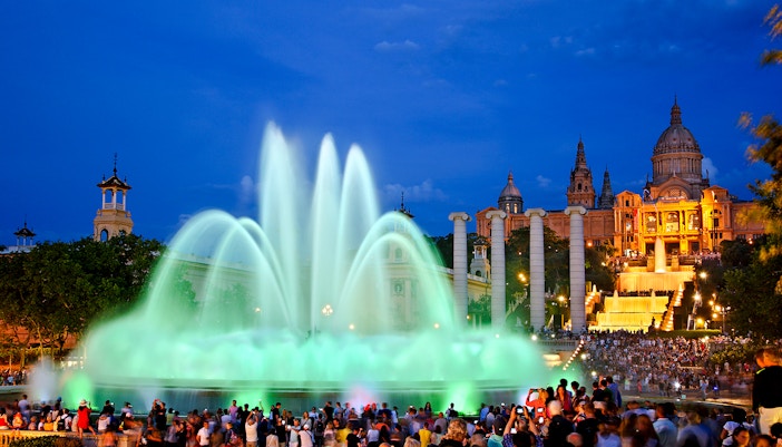 Magic fountain show at Montjuic hill, Barcelona, with crowds watching illuminated water display.