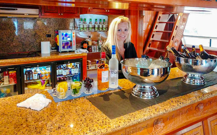 Luxury yacht serving area with drinks, ice buckets, and a smiling staff member.