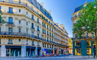 Paris Le Marais street with traditional architecture, balconies, and iron fences at a crossroad.