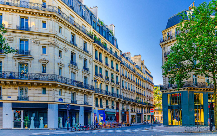 Paris Le Marais street with traditional architecture, balconies, and iron fences at a crossroad.