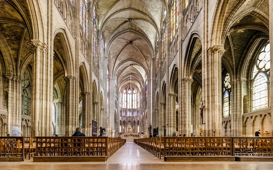 Interior view of Basilica of Saint-Denis with vaulted ceilings and stained glass windows.