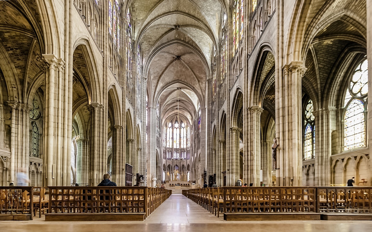 Interior view of Basilica of Saint-Denis with vaulted ceilings and stained glass windows.